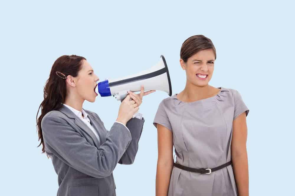 11686698 - businesswoman with megaphone yelling at colleague against a white background