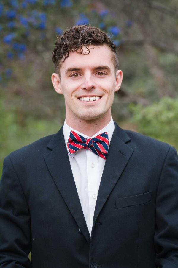Smiling man in a suit and bow tie, likely a speaker for the "Careers in Ceramics & Glass" webinar.