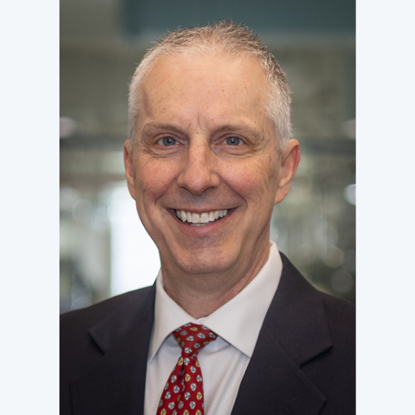 Professional man in suit and tie smiling confidently at the camera.