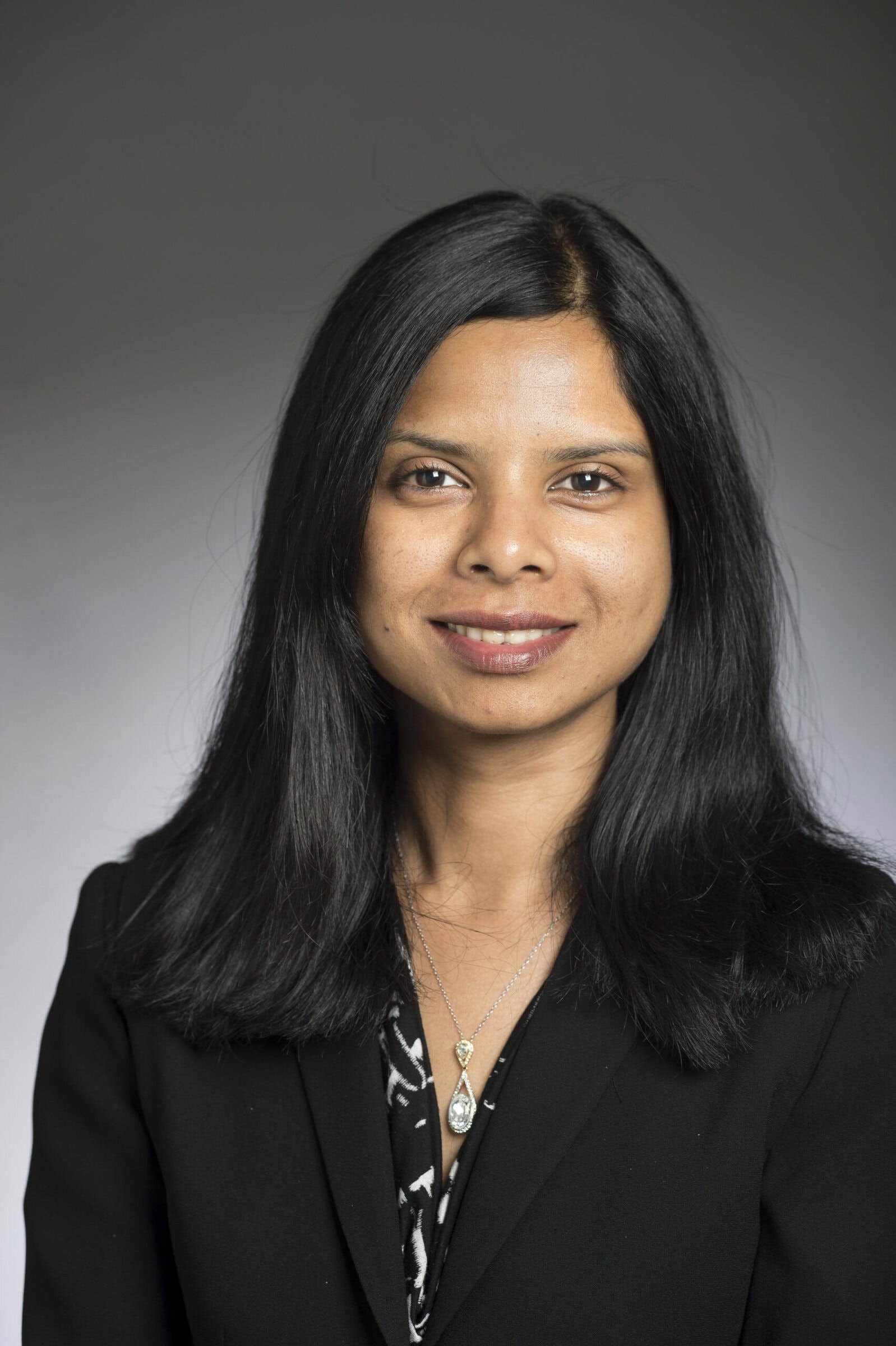 Portrait of Reeja Jayan, wearing a black blazer and a silver necklace.